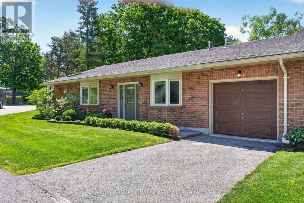 Side view of a brick townhouse featuring a garage door and front entrance. - 1 - 90 Parklawn Boulevard, Brock
