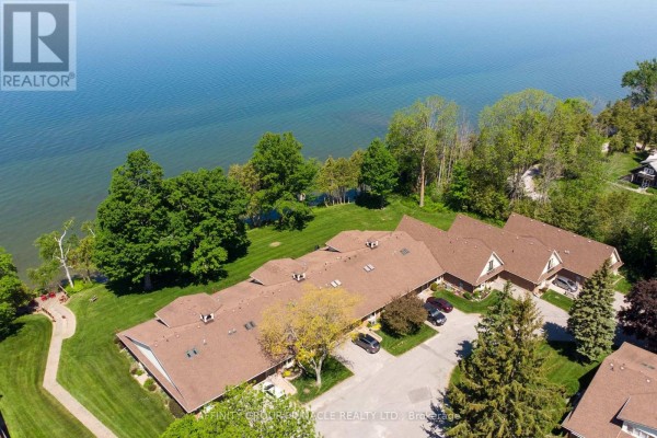 Aerial view of townhouses beside a large body of water with treed shoreline. - 1 - 90 Parklawn Boulevard, Brock