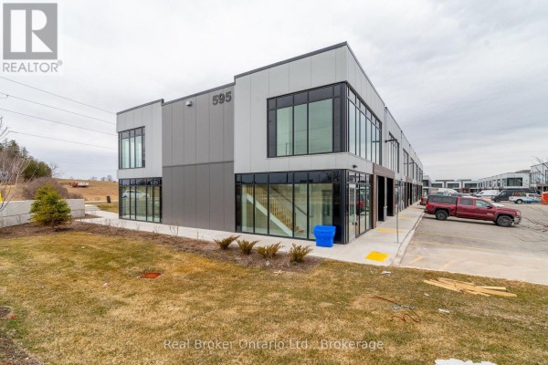 Side view of a commercial building with large windows and grey paneling. - 1 - Full - 595 Hanlon Creek Boulevard, Guelph