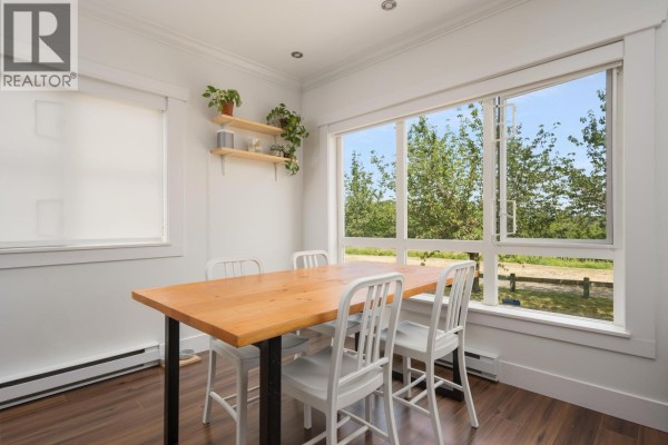 Dining area with a wooden table, white chairs, and large windows overlooking trees. - 1 13028 No. 2 Road, Richmond