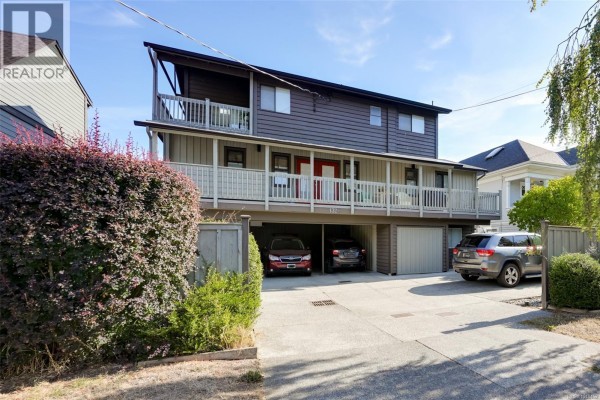Narrow covered walkway with grey siding, potted plants, and a clear roof. - 1 132 Michigan St, Victoria