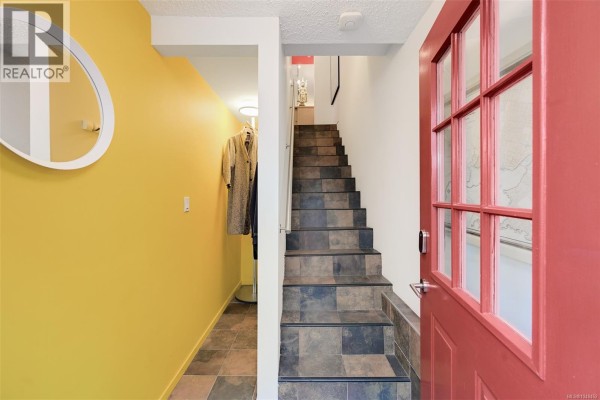 Interior staircase with a metal handrail leading to a brightly lit landing. - 1 132 Michigan St, Victoria