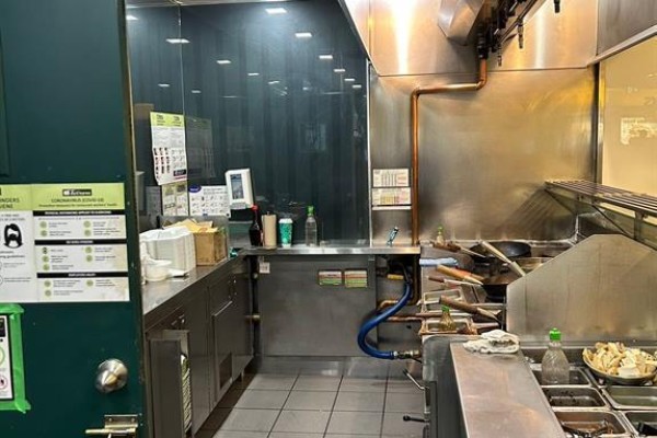 Commercial kitchen with stainless steel counters, woks, ventilation hood, and shelving. - 1-134 - 100 City Centre Drive, Mississauga