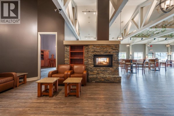 Lounge area with modern seating, a stone fireplace, and a bar counter in the background. - 1 1600 Stroulger Rd, Nanoose Bay