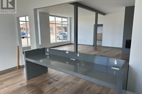Interior commercial space with a grey reception desk, exposed columns, and view to another room. - 1-2 - 24707 Woodbine Avenue, Georgina