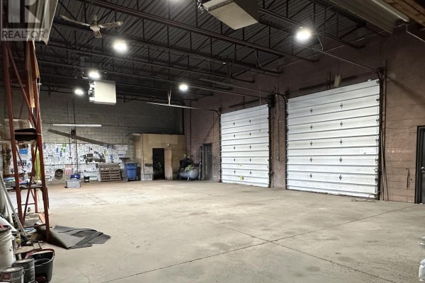 Interior view of a warehouse space with concrete floor, high ceiling, and two large bay doors. - 1-2 - 24707 Woodbine Avenue, Georgina