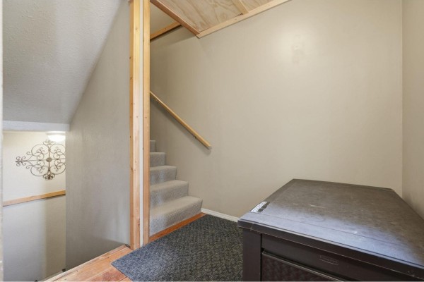 Interior view of a staircase with beige walls, wooden handrail, and a large dark storage chest. - 1 20944 Snowflake Crescent, Agassiz