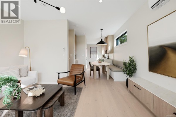 Living area with armchair, sofa, dining table, built-in bench seating, and light wood floors. - 1 2100 Allenby St, Oak Bay