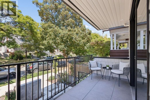 Small balcony with chairs and side table overlooking a residential street with trees. - 1 2124 E 8 Avenue, Vancouver