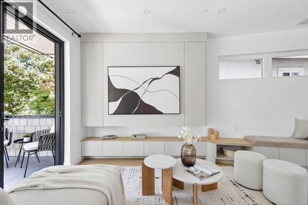 Living room with built-in white cabinetry, large TV, modern coffee table, and seating. - 1 2124 E 8 Avenue, Vancouver