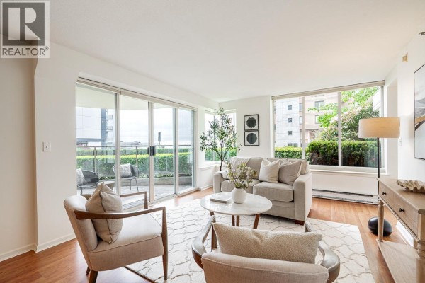 Living room featuring two armchairs, a sofa, glass patio doors, and large windows with greenery outside. - 1 2243 Bellevue Avenue, West Vancouver