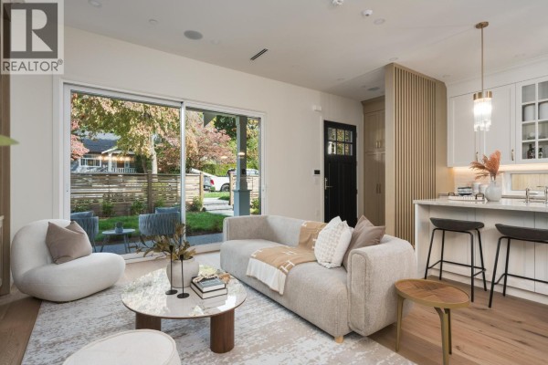 Living room with sofa, view of backyard and street, and kitchen island with bar stools. - 1 2344 W 45th Avenue, Vancouver
