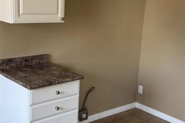 Kitchen counter with drawers and a granite-style laminate countertop, beige walls. - 1 303 Leola Street, Winnipeg