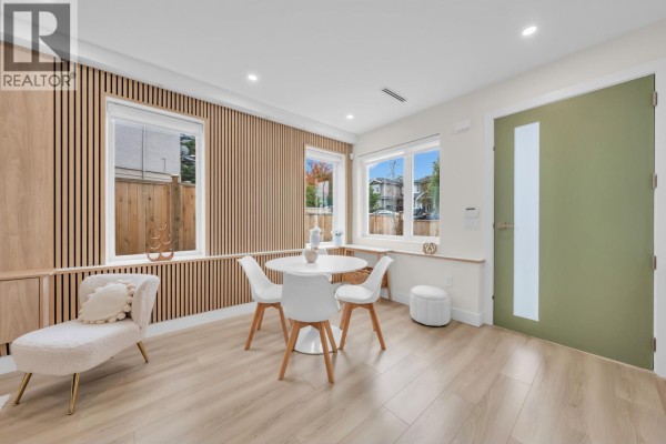 Living and dining area with light wood slat walls, white table, chairs, and modern couch. - 1 3581 Haida Drive, Vancouver