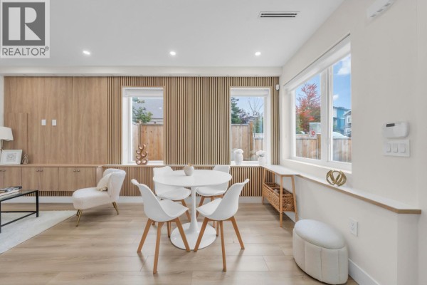 Open-concept living and dining area with light wood slat walls and large windows. - 1 3581 Haida Drive, Vancouver