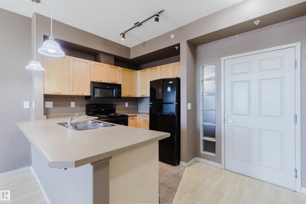 View from balcony overlooking a parking lot, trees, and a highway overpass. - #1-405 4245 139 Av Nw, Edmonton
