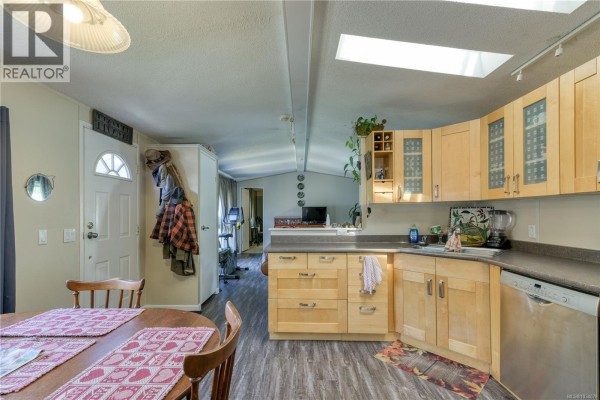 View of the kitchen and dining area from the front door, with a skylight above. - 1 5250 Beaver Harbour Rd, Port Hardy