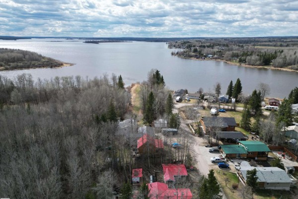Aerial view of houses and trees with a large lake visible in the distance. - #1 54114 Rge Road 52, Rural Lac Ste  Anne County