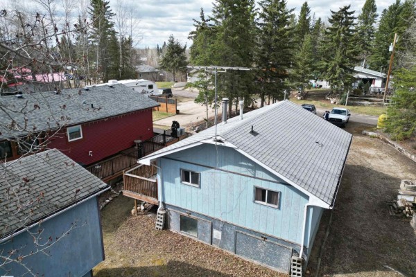 Rear aerial view of a light blue house with a red neighboring house and parked vehicles. - #1 54114 Rge Road 52, Rural Lac Ste  Anne County