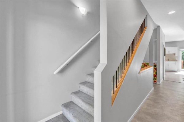Interior view of a grey staircase with carpeted steps and a wooden railing. - 1 548 Dufferin Avenue, Selkirk