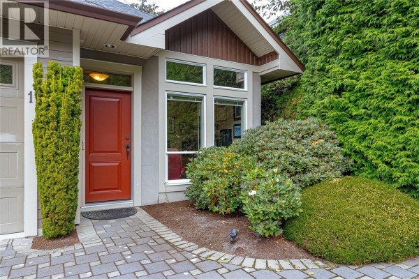 Close-up of the red front door, entryway windows, and landscaping with evergreen bushes. - 1 551 Bezanton Way, Colwood