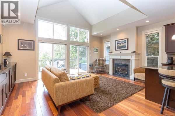 Living room with vaulted ceiling, gas fireplace, large windows, and access to a deck. - 1 551 Bezanton Way, Colwood