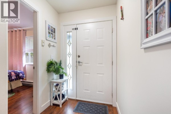 Entryway with a front door, small table, and decorative photos on the wall. - 1 5706 Ebbtide Street, Sechelt