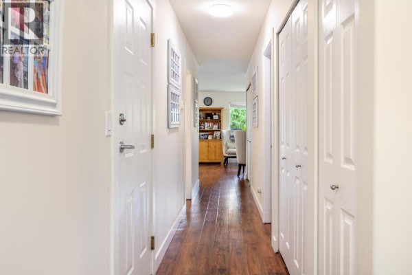 Cluttered garage filled with storage bins, bicycles, and various items on shelves. - 1 5706 Ebbtide Street, Sechelt