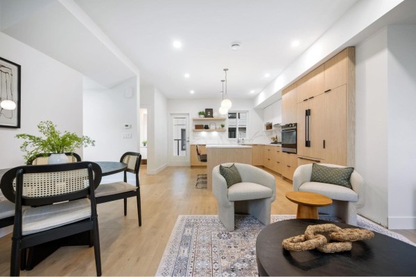 Open concept living and dining area with modern furniture and light wood floors. - 1 5993 143 Street, Surrey