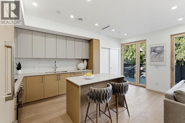 Kitchen view showing ample cabinet space, stainless steel appliances, and a central island with seating. - 1 60 E 17th Avenue, Vancouver