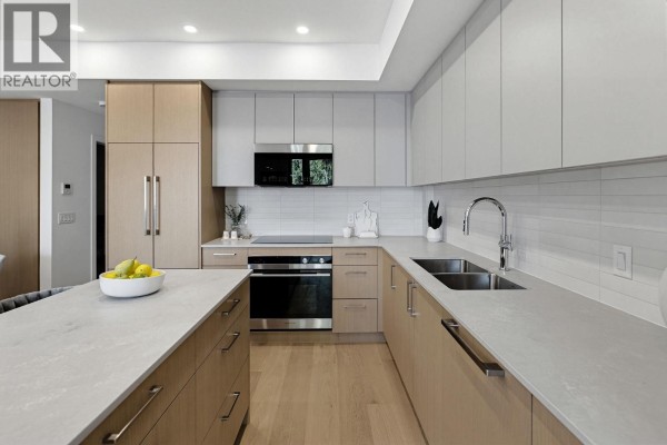 Spacious open-concept living and dining area adjacent to a modern kitchen with an island and seating. - 1 60 E 17th Avenue, Vancouver