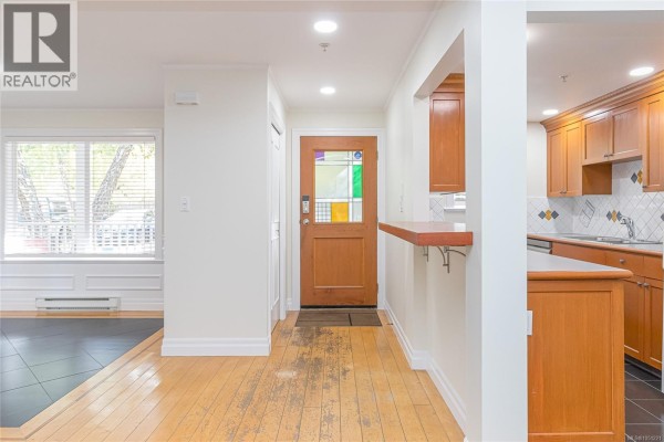 View of the entryway, dining area, and kitchen with wood cabinets and a breakfast bar. - 1 649 Admirals Rd, Esquimalt