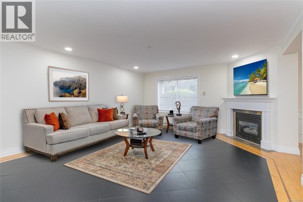 Living room with a fireplace, sofa, chairs, coffee table, and a large framed landscape painting. - 1 649 Admirals Rd, Esquimalt