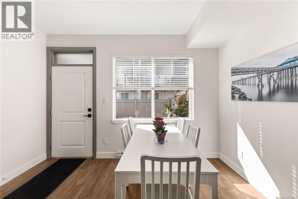 Interior view of dining area showing white table, chairs, window, and entrance door. - 1 796 Island Hwy S, Campbell River