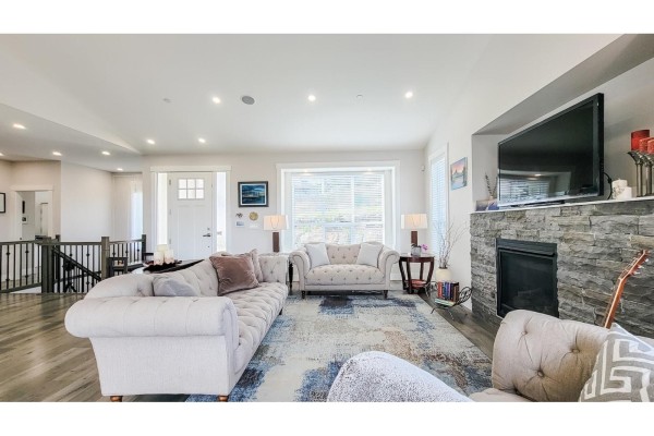 Bedroom with a dark wood bed frame, side tables, and a view into a wet bar area. - 1 8295 Nixon Road, Eastern Hillsides, Chilliwack