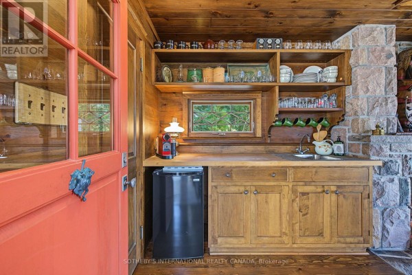 Kitchenette with wooden cabinets, sink, mini fridge, stone fireplace, and orange door - 1 A307 Island The Archipelago