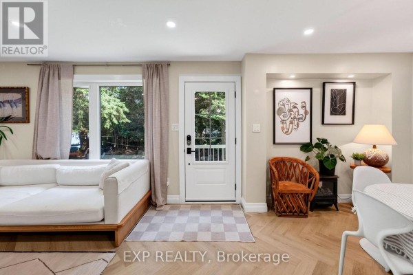 Interior view of a living room showing a white sofa, wood floor, and a door to the outside. - 1 Aird Court, Georgina