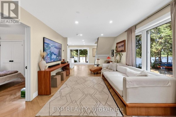 Spacious living room with a long white sectional sofa, television, and large windows with water views. - 1 Aird Court, Georgina
