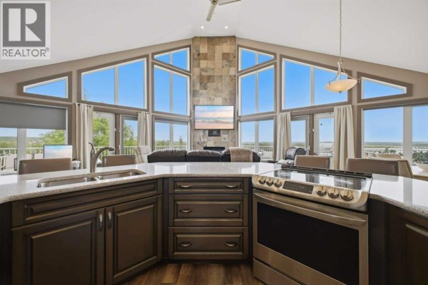 Large kitchen with stainless steel refrigerator, dark grey cabinets, and island with sink. - 1 Aspen Rise, Parkland Beach