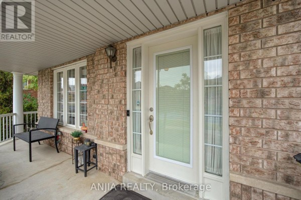 Front porch details including a chair, side table, brick facade, and glass front door. - 1 Aylesbury Gate, Markham