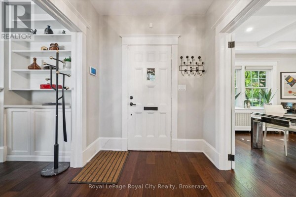 Interior front entrance with white door, built-in shelves, coat rack, and wood floors. - 1 Barber Avenue, Guelph