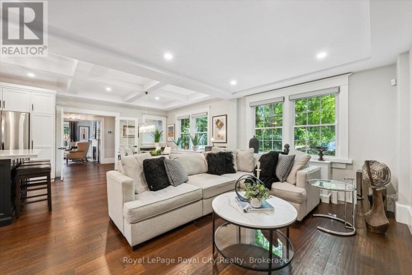 Living room with coffered ceiling, sectional sofa, and view of green trees. - 1 Barber Avenue, Guelph
