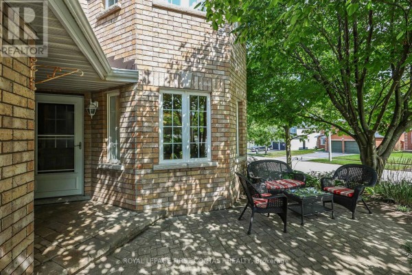 Front porch with brick exterior and seating area under a tree. - 1 Brown Wood Drive, Barrie