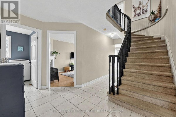 Interior foyer with a winding staircase, tiled floor, and laundry room. - 1 Brown Wood Drive, Barrie