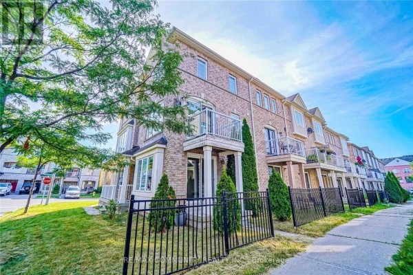 Side exterior of a brick townhouse featuring a balcony and a black metal fence. - 1 Burnsborough Main Street, Ajax