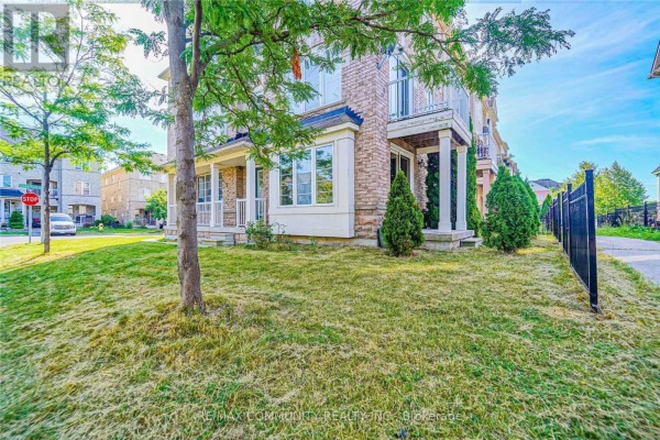 Ground level view of a brick townhouse with a front porch and green lawn. - 1 Burnsborough Main Street, Ajax