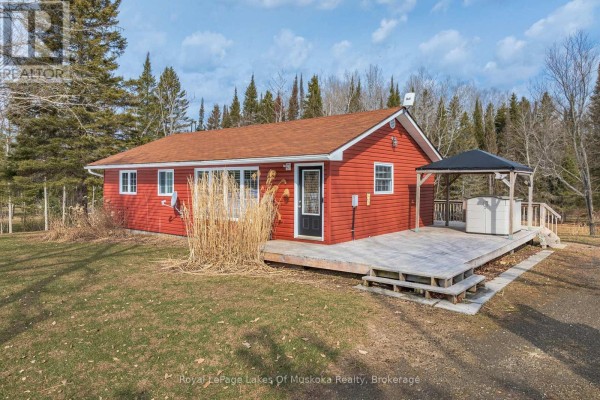 Close-up exterior view of a red sided house with a black door, wooden deck, and tall dry grass. - 1 Christopher Lane, Armour