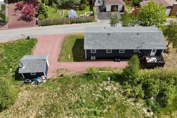 Aerial view of a dark blue bungalow and detached garage on a sloped lot with a gravel driveway. - 1 Coady's Place, Marystown