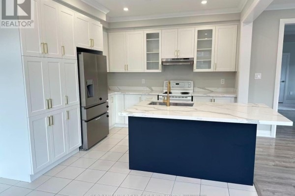 Modern kitchen with white cabinets, a dark blue island with a marble countertop, and stainless steel appliances. - 1 Copperhill Heights N, Barrie