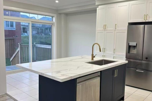 Kitchen with a large island, stainless steel refrigerator, white cabinets, and a sliding glass door to the backyard. - 1 Copperhill Heights N, Barrie